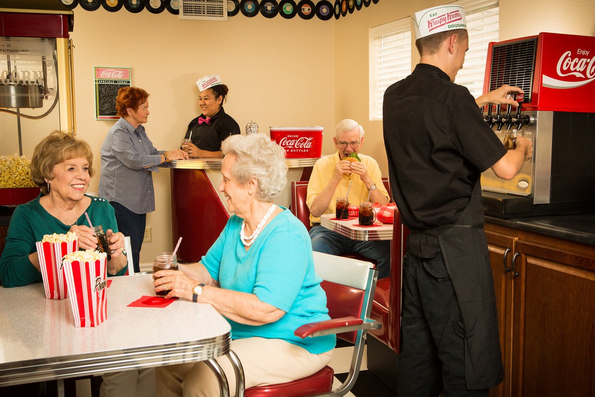 A retro-style diner where people enjoy their meals and a waiter attends to customers.