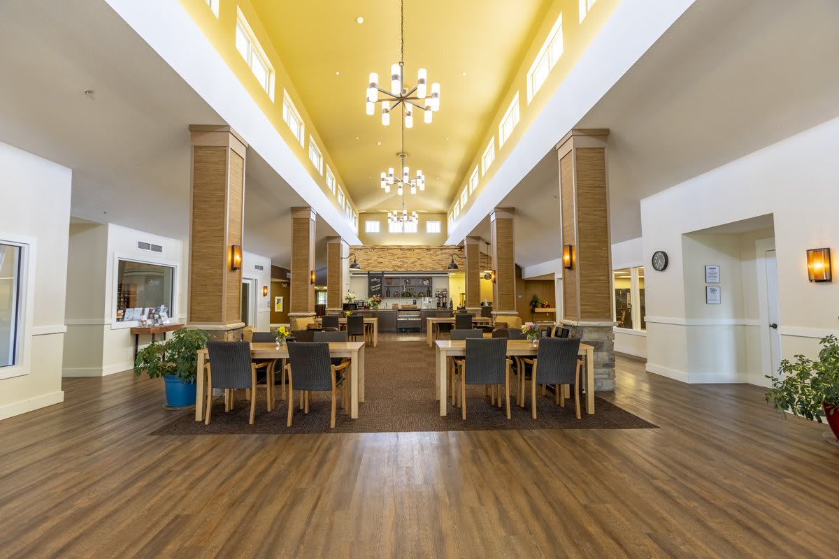A spacious dining area with modern decor, featuring chandeliers and wooden flooring.