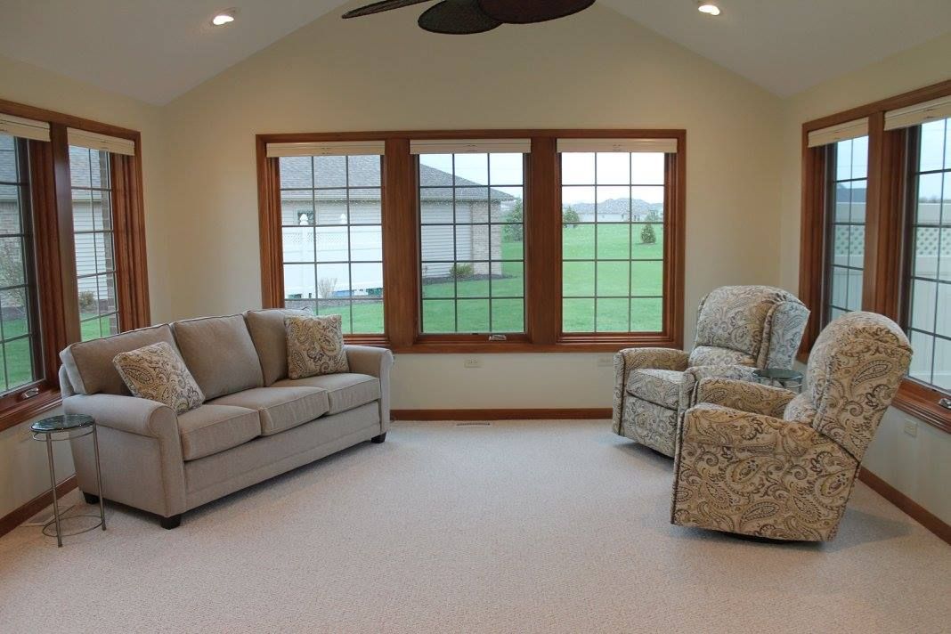 A cozy living room with a sofa, armchair, and large windows.