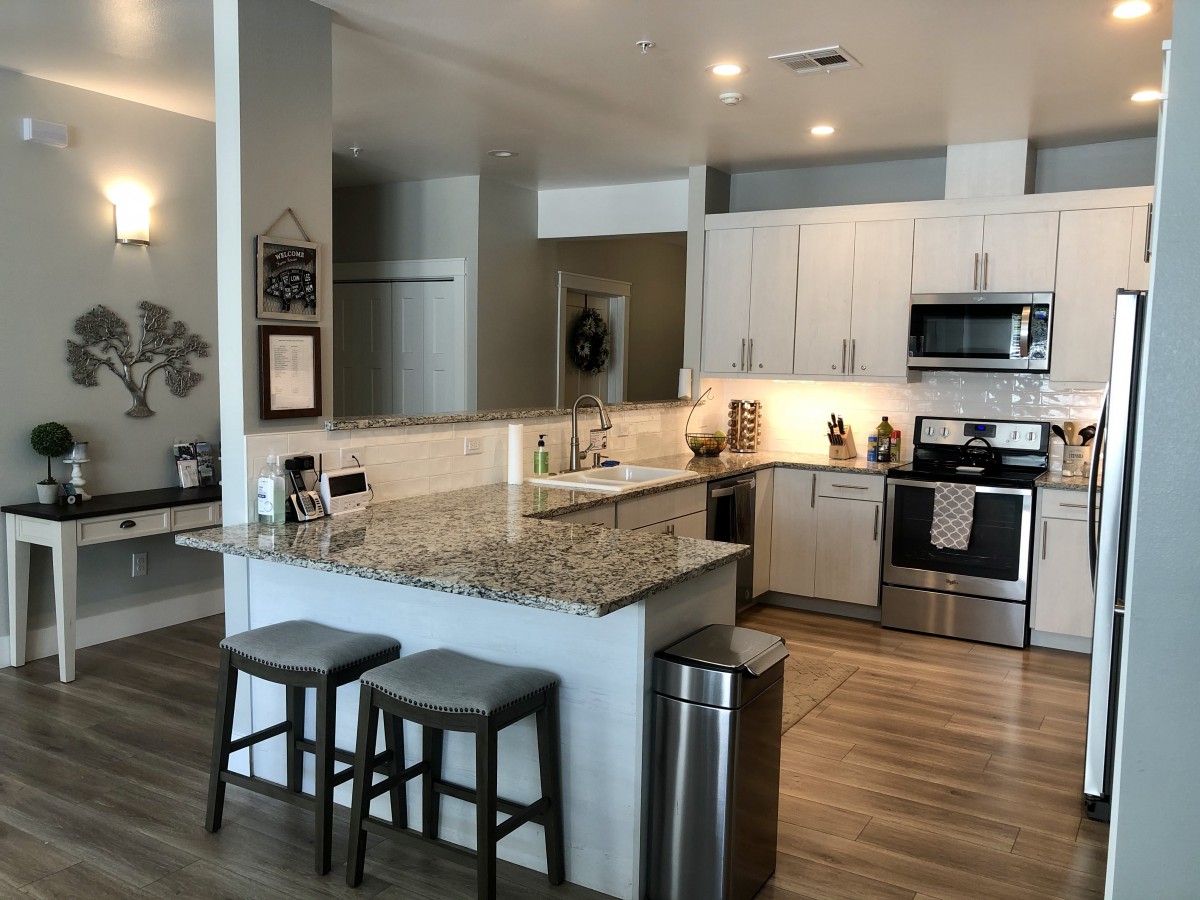 A modern kitchen with sleek countertops and barstools, featuring a stylish open layout and contemporary appliances.