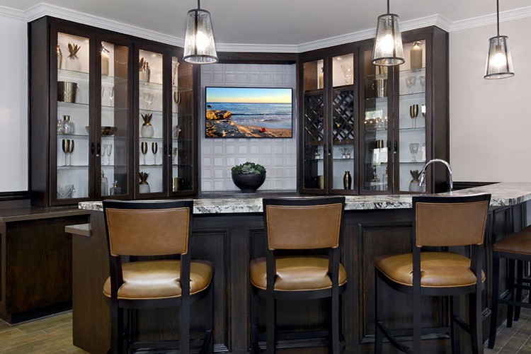 A stylish home bar featuring modern seating, elegant lighting, and well-organized cabinets.