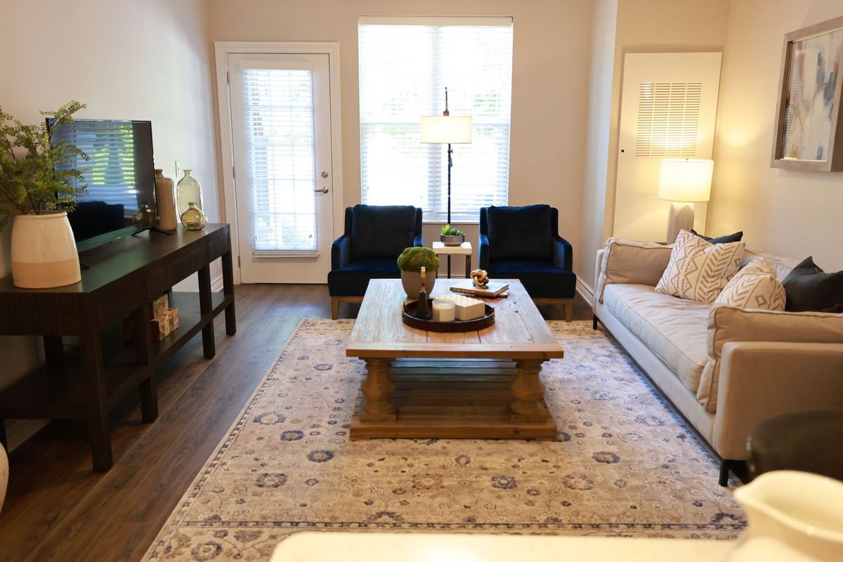 A cozy living room with a wooden coffee table, sofa, and chairs arranged on a patterned rug.