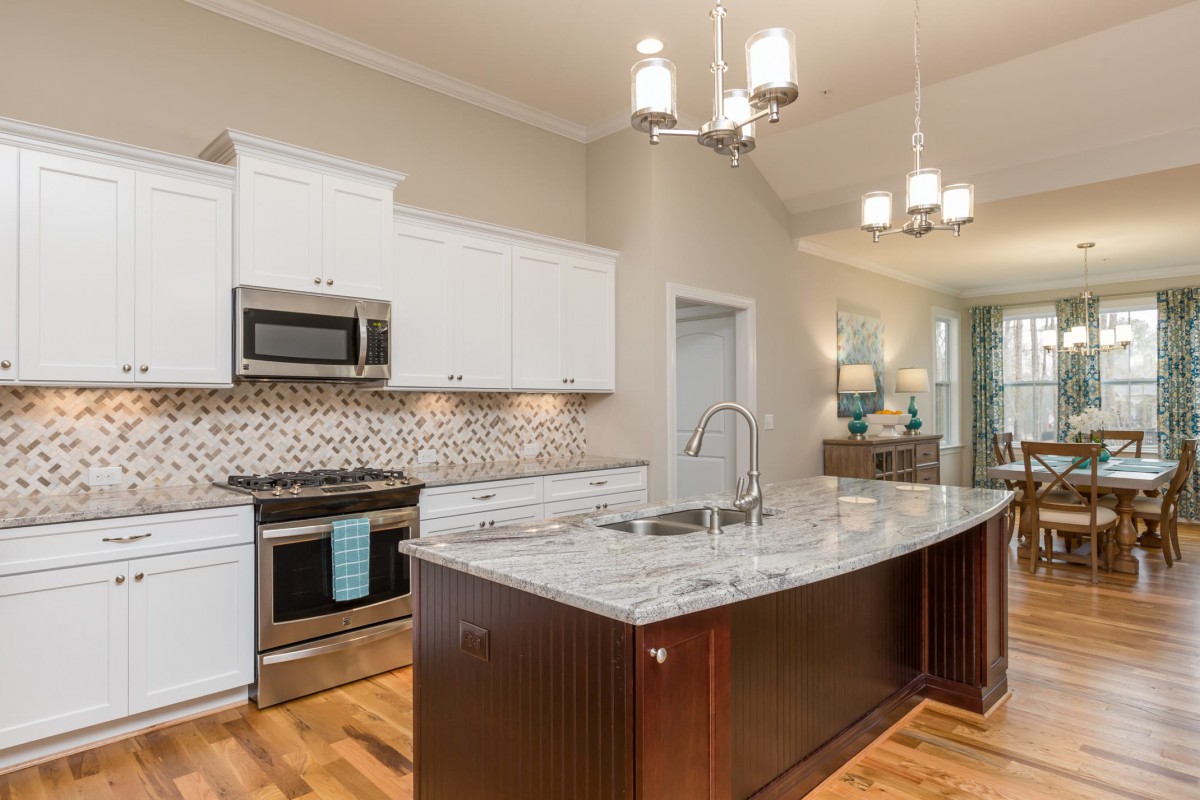 A modern kitchen with stainless steel appliances and a granite island countertop.