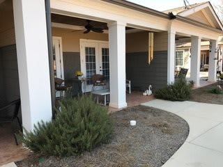 A cozy patio area with chairs and a table next to a landscaped pathway.