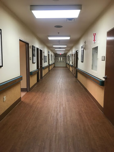 A view of a well-lit hospital hallway with doors on either side.