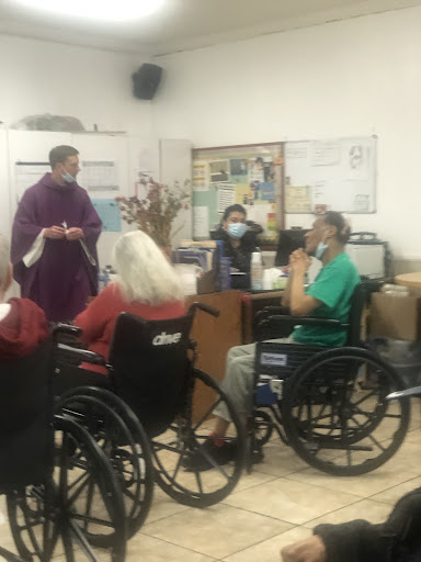 A community gathering in a care facility where seniors engage in a group discussion.