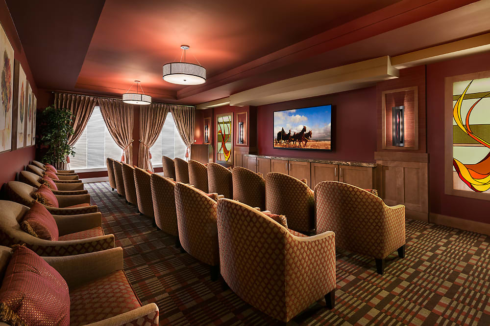 A cozy home theater with rows of upholstered chairs and a large screen.