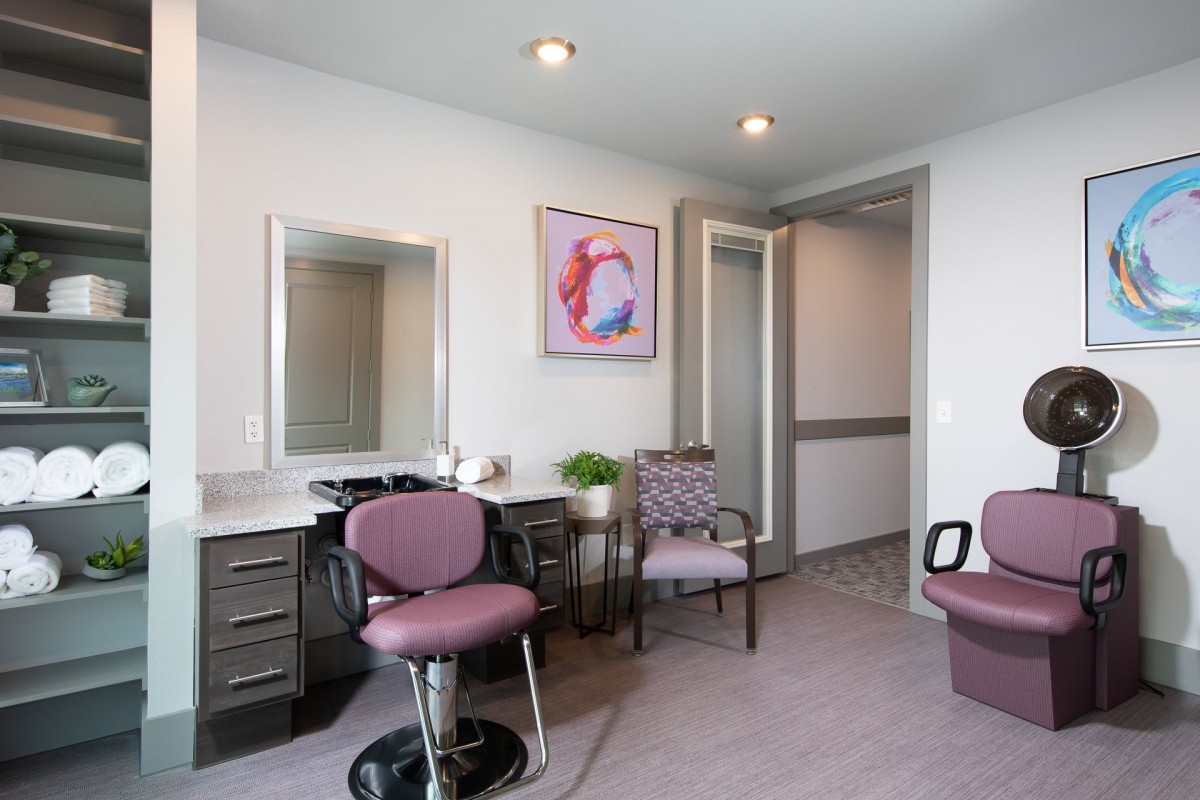 A modern salon interior with stylish chairs, a mirror, and vibrant artwork on the wall.