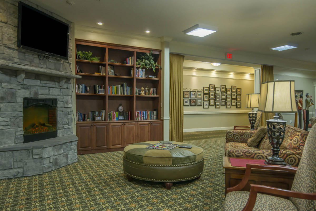 A cozy living room with a large bookshelf and stone fireplace.