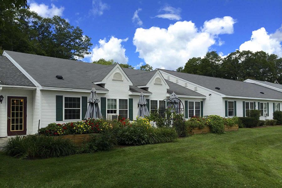 A charming white residential home with a well-maintained garden under a clear blue sky.