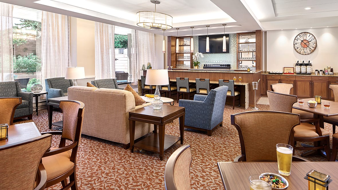 A cozy lounge area with comfortable seating and a bar in the background.