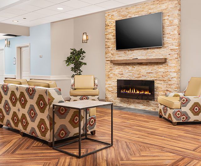 A modern lobby with a cozy seating area, featuring a fireplace and television.
