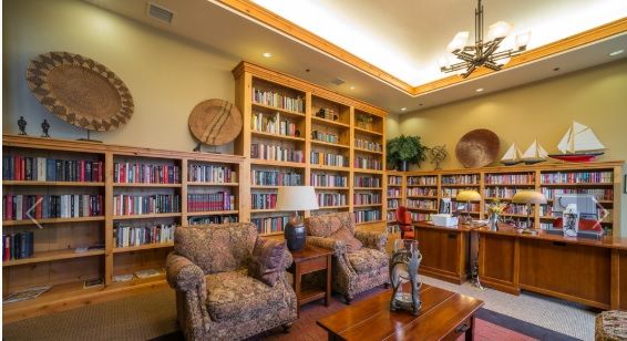 A cozy library with wooden bookshelves and comfortable armchairs, illuminated by warm lighting.