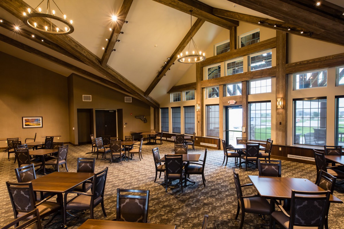 A cozy dining area with wooden beams, tables, and large windows.