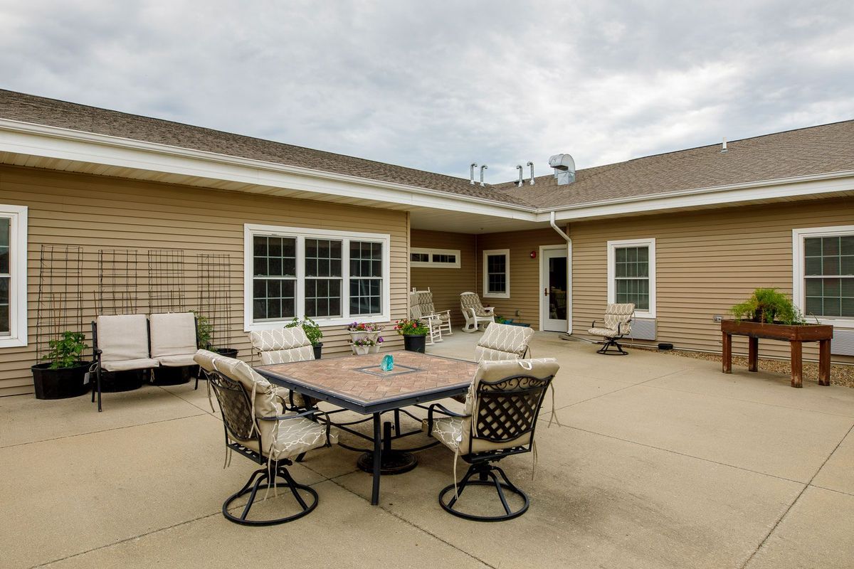 A spacious patio area with a table and chairs set against the backdrop of a house exterior.