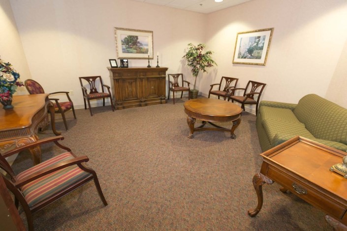 A cozy waiting room with wooden furniture and artwork on the walls.
