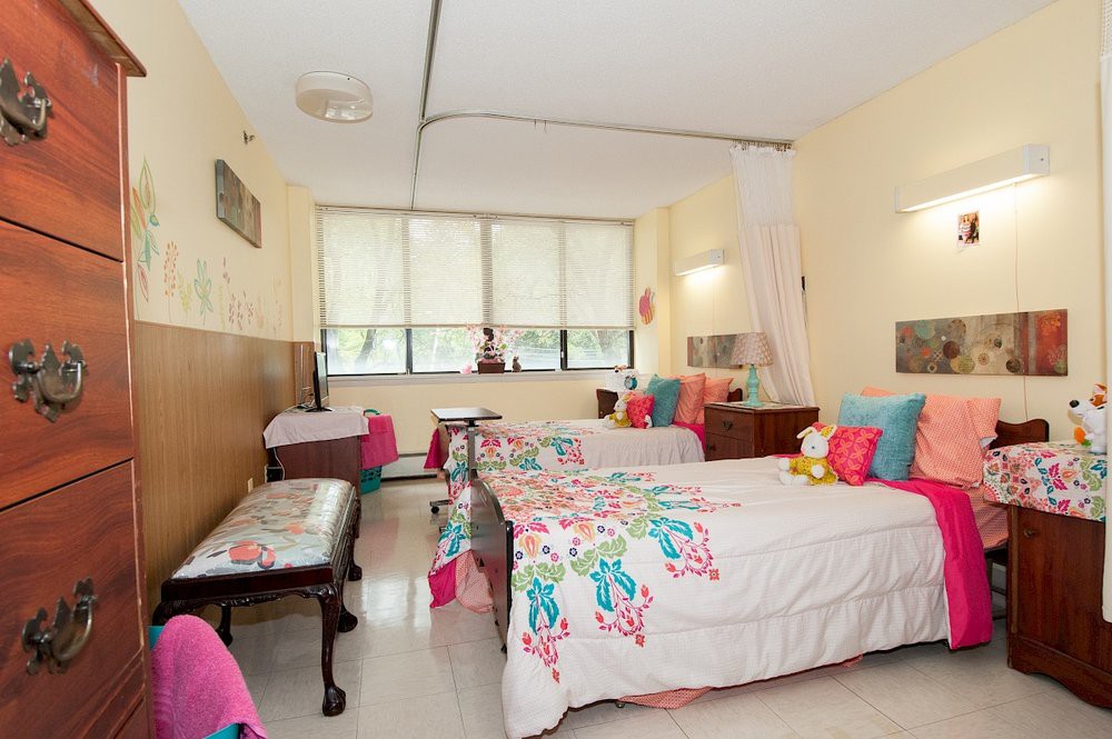 A colorful, well-decorated bedroom with twin beds and ample natural light.