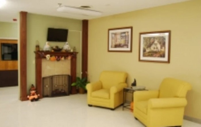 A cozy living room with yellow chairs, a decorated fireplace, and framed artwork on the walls.