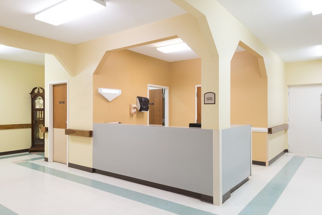 A reception area in a hospital with a front desk and beige walls.