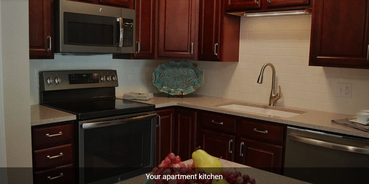 Modern apartment kitchen with wooden cabinets and appliances.