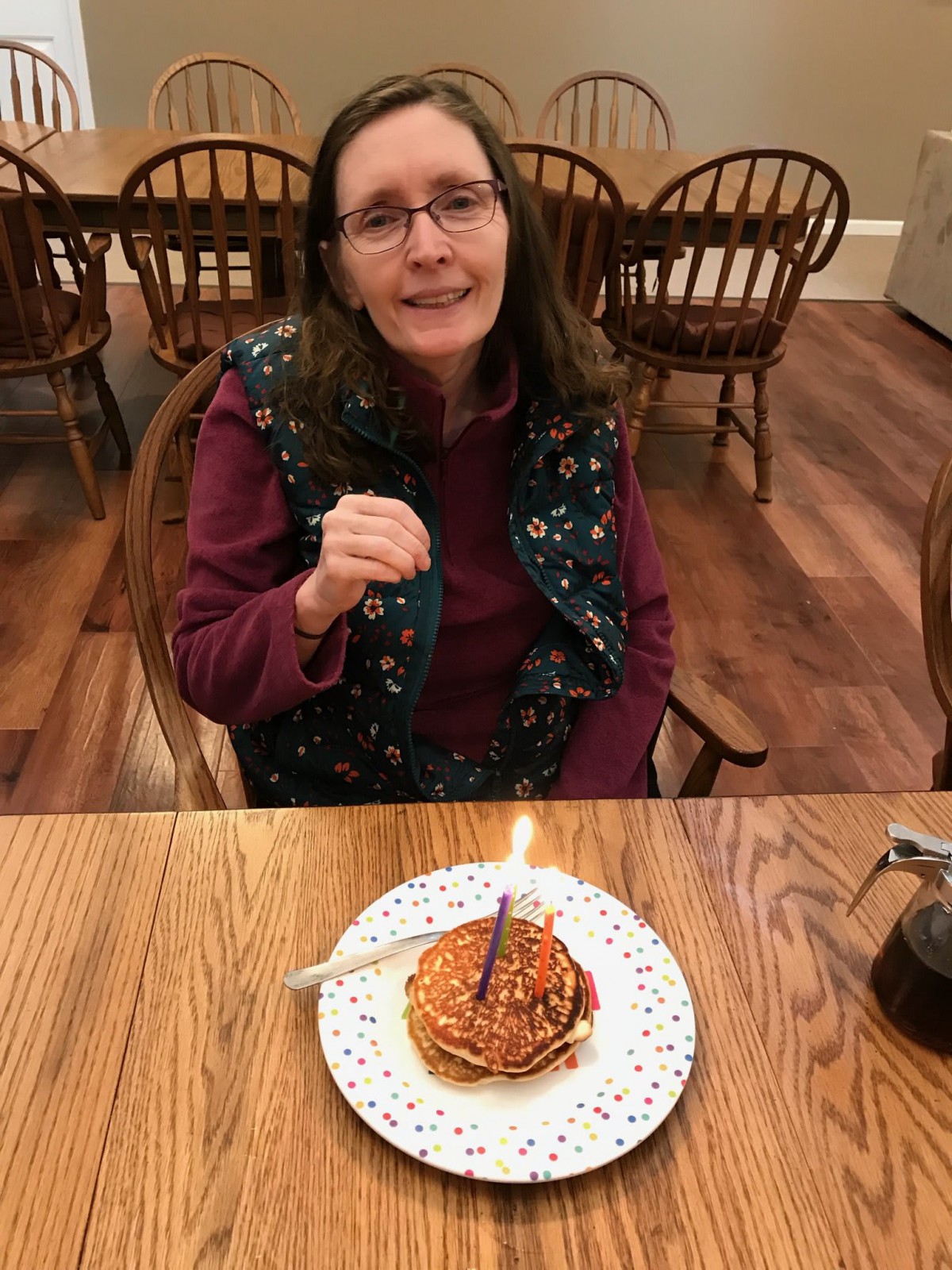 A person celebrating a birthday with a cake and candle at a table.