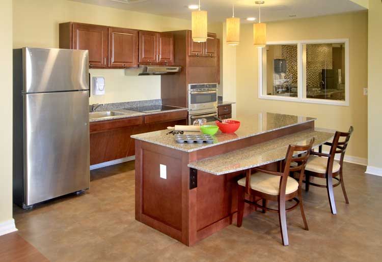 A modern kitchen with stainless steel appliances, wood cabinets, and an island counter with seating.