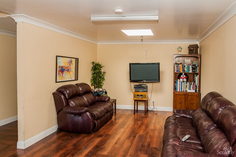 Cozy living room with leather sofas, a wall-mounted TV, and a bookshelf.
