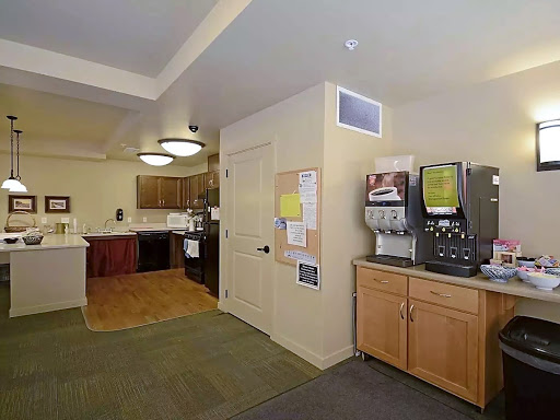 A cozy kitchen area featuring wooden cabinets, a coffee machine, and open space.
