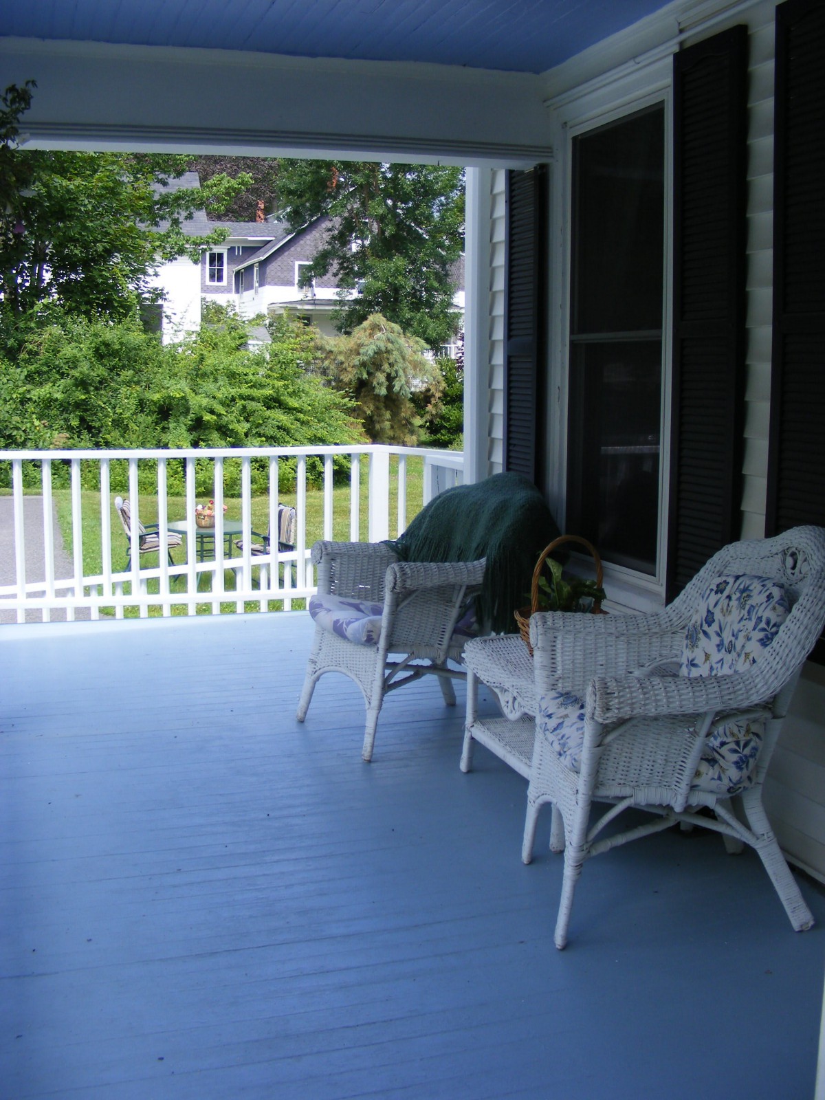 A cozy porch with wicker furniture and a view of the garden.
