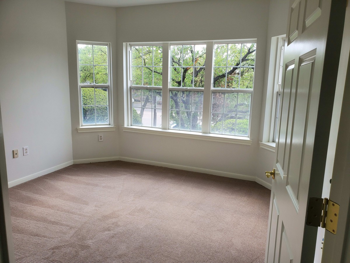 A bright and spacious room with large windows and carpeted flooring.