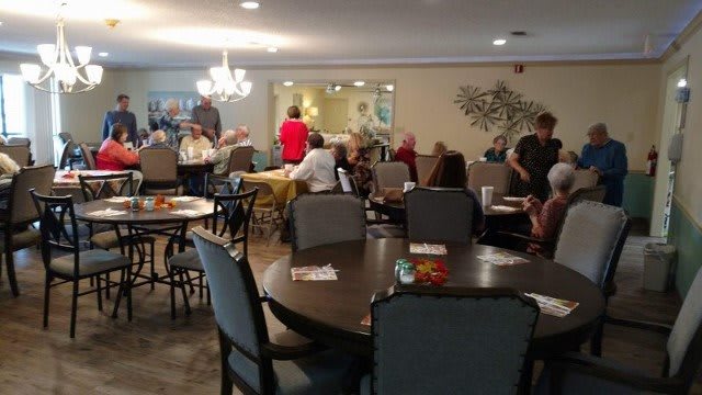 A group of people socializing in a dining area with tables and chairs.