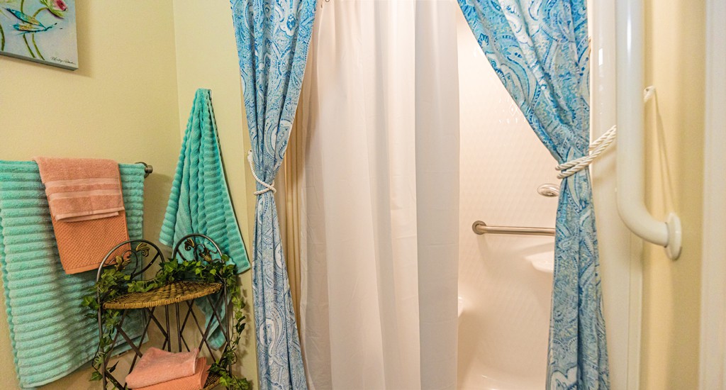 A cozy bathroom featuring a shower with elegant blue curtains and neatly arranged towels.