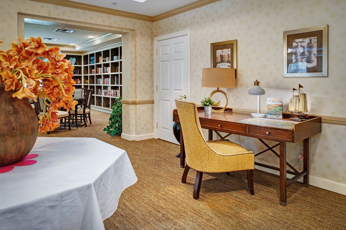 A cozy interior of a library room with a desk, chair, and bookshelves.