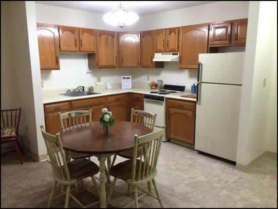 A cozy kitchen with wooden cabinets and a dining table.