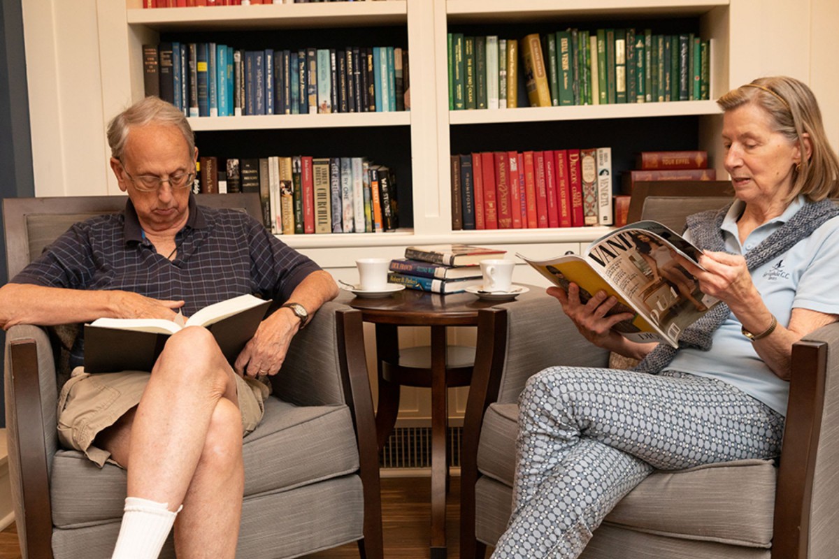 Two adults sitting in a cozy library, reading and enjoying a quiet moment.