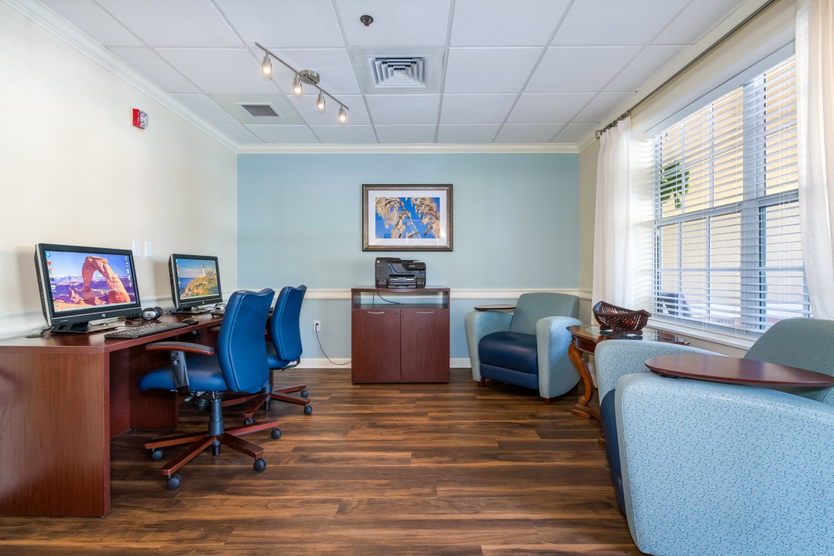 A well-lit office space featuring computers, blue chairs, and a wooden floor.