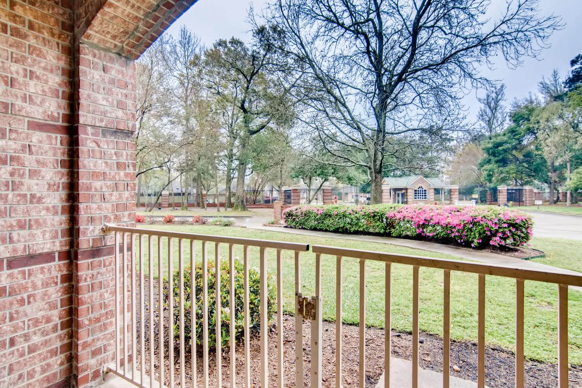 A view from the balcony overlooking a garden with trees and flowers.