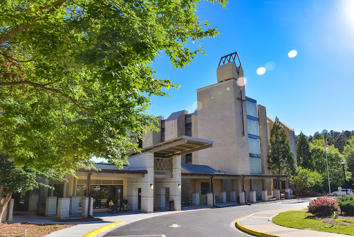A modern hotel building set against a clear blue sky, surrounded by trees.