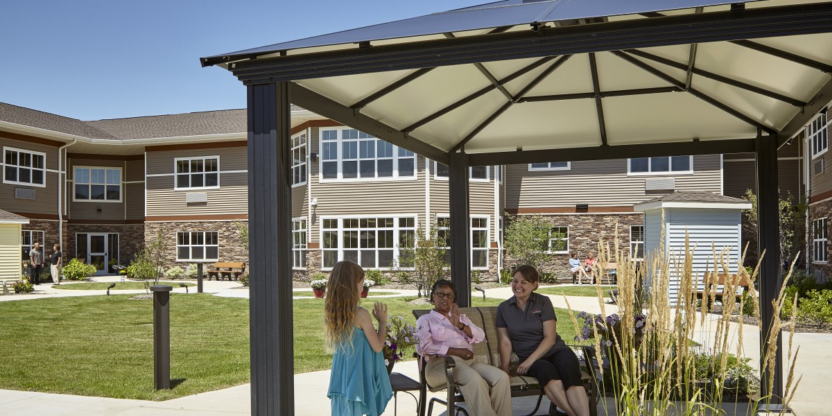 A group of people enjoying a conversation under a gazebo on a sunny day in front of a building.