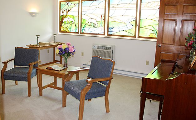 A cozy interior with a chair, table, and stained glass windows.