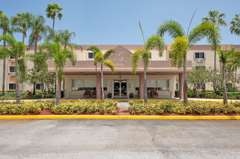 A tropical-style hotel entrance with palm trees and well-maintained landscaping.