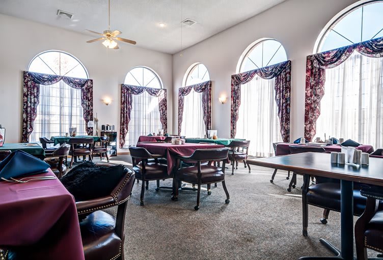 Spacious dining area with elegant tables and chairs, featuring large windows and decorative curtains.