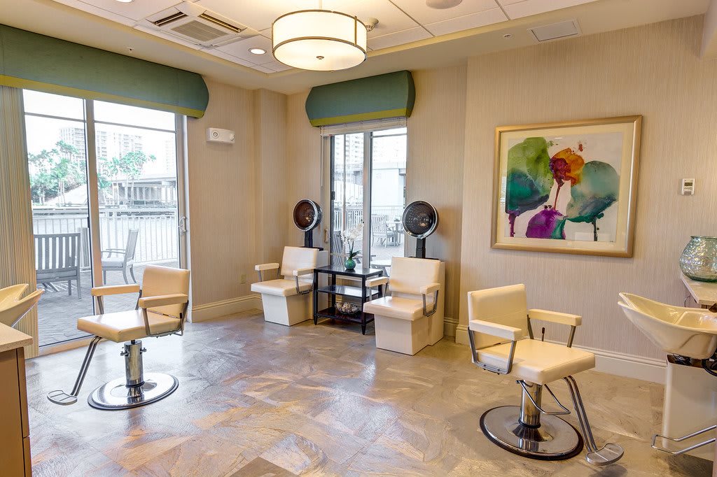 A brightly lit hair salon with stylish chairs, modern decor, and colorful artwork on the wall.