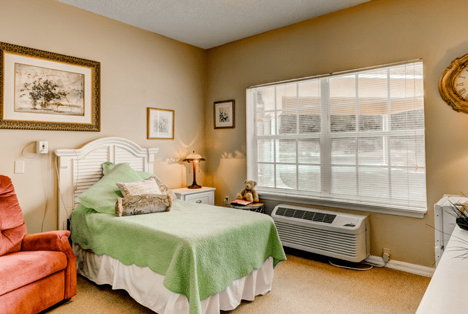 A cozy bedroom with a single bed, bedside table, and window light.
