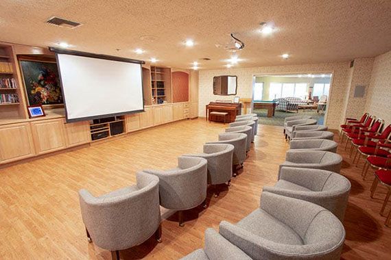 A modern conference room equipped with comfortable seating and a large projector screen.