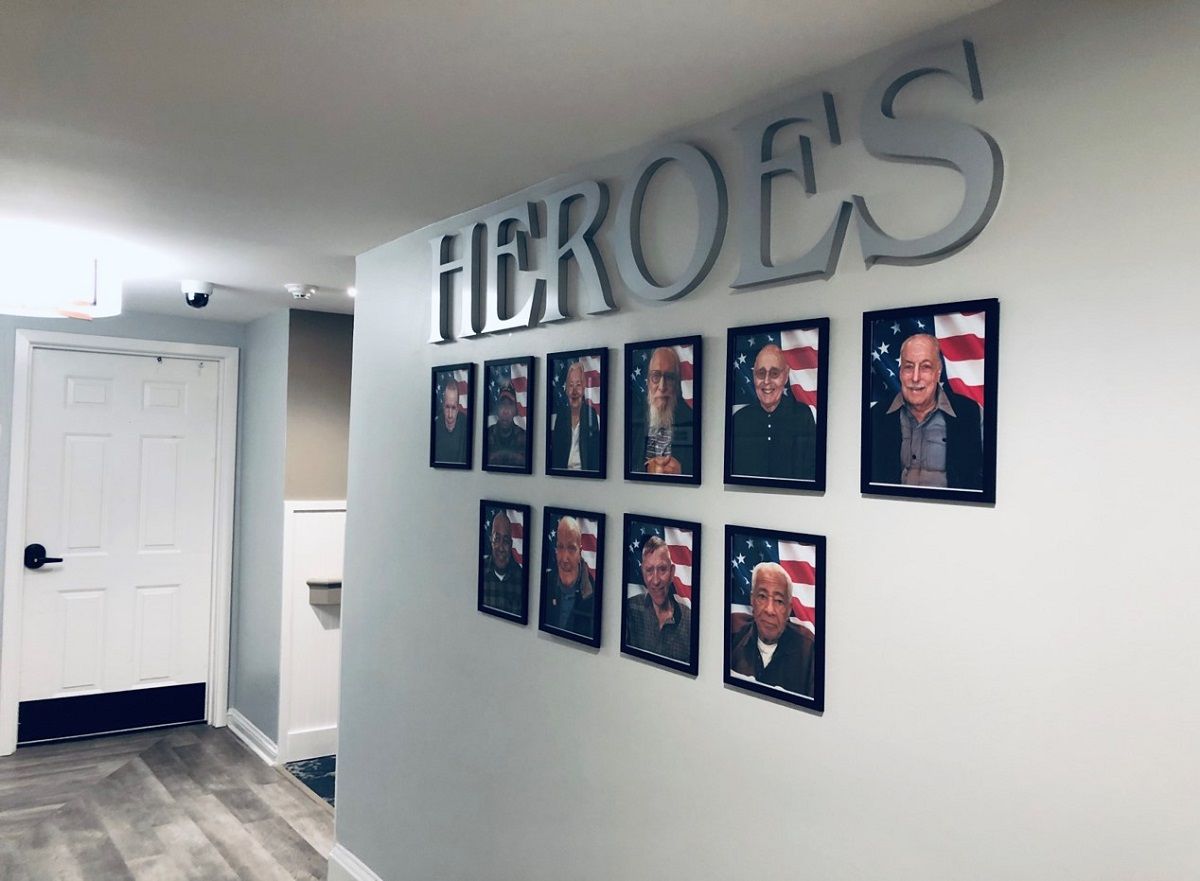A wall displaying framed photographs titled 'HEROES' as a tribute.