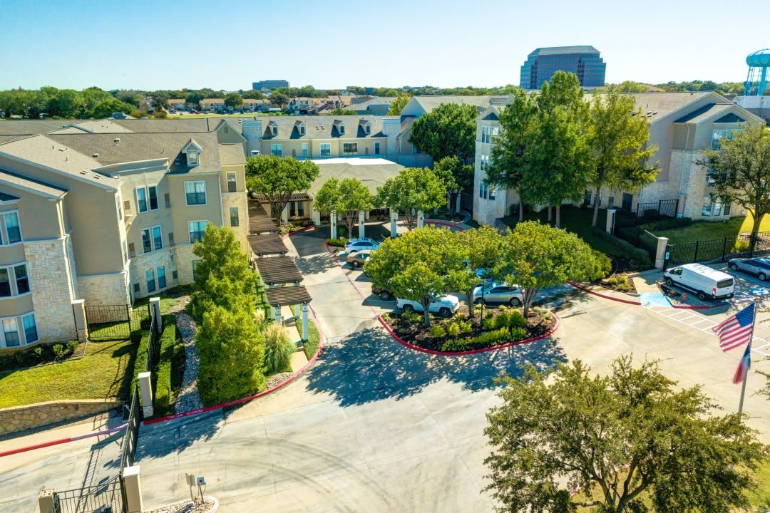 Aerial view of a residential area surrounded by greenery and a parking lot.