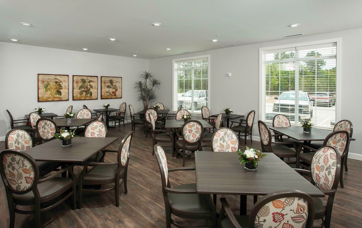 A spacious dining room with elegantly arranged tables and chairs, bright natural lighting, and tasteful decor.