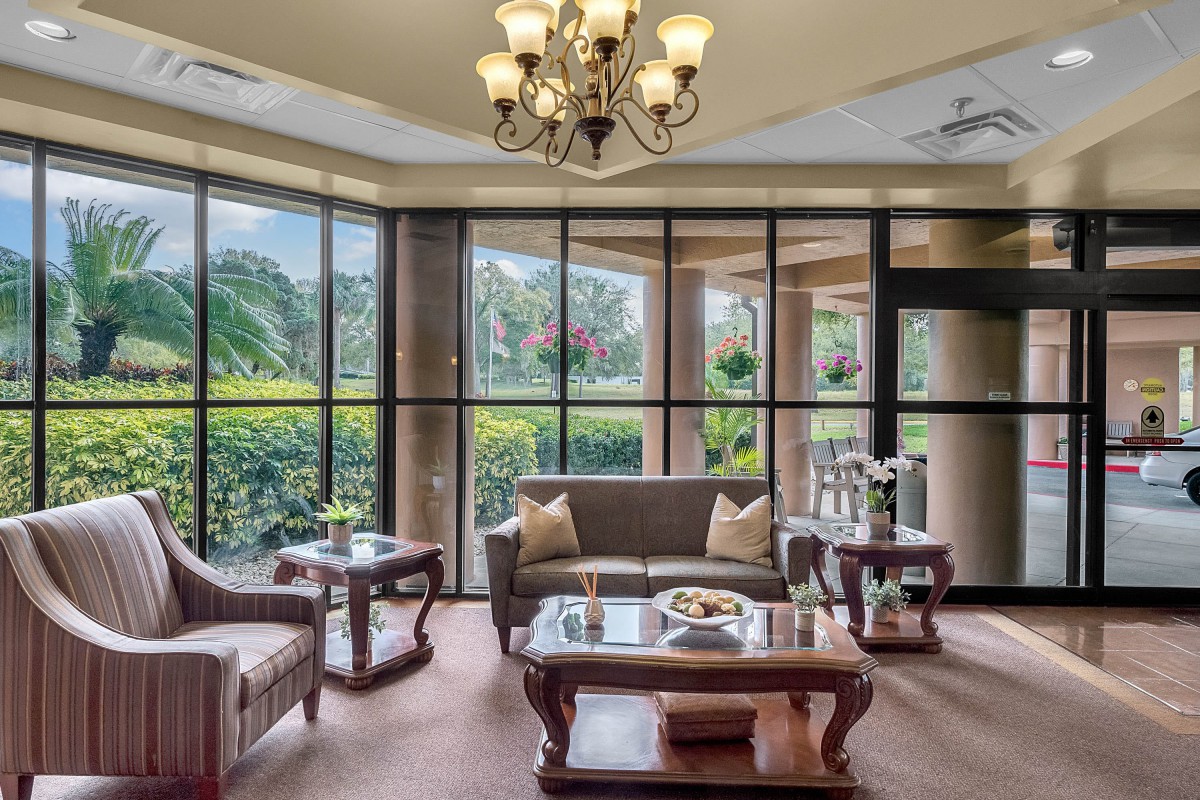 A spacious living room with large windows, elegant furniture, and a decorative chandelier.