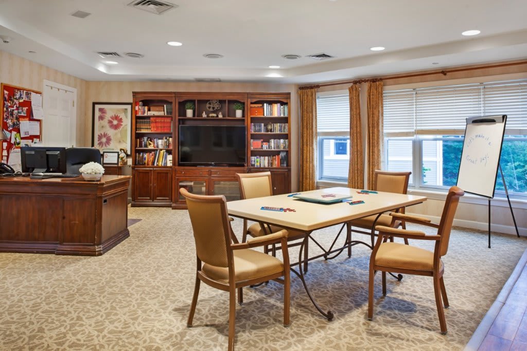 A well-furnished conference room with a meeting table, chairs, bookshelves, and a television.
